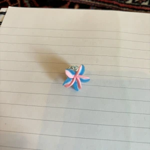 Blå och rosa blomformad brosch - Charmig brosch i form av en blomma med blå och rosa kronblad. Perfekt för att ge en färgglad touch till din outfit. Broschen har en silverfärgad baksida som gör den enkel att fästa på kläder eller accessoarer.