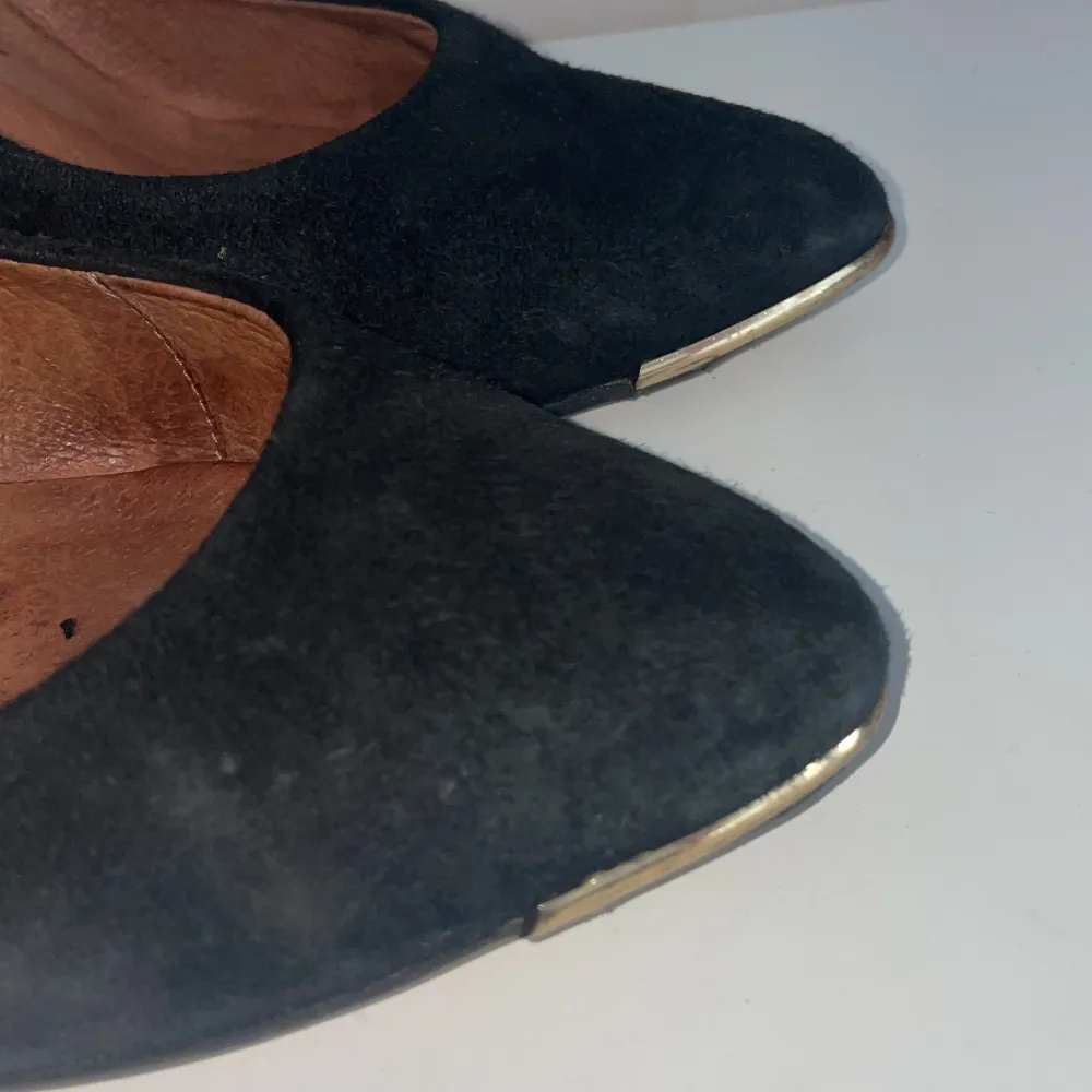 Eleganta svarta pumps i mocka med spetsig tå och klack( 9 cm). Skorna har en stilren design med en subtil gulddetalj vid tån. Perfekta för en chic look.. Kengät.