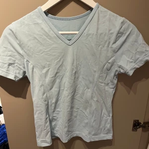 Ljusblå t-shirt från Airflex - Säljer en ljusblå t-shirt från Airflex med v-ringning och korta ärmar. Tillverkad i ett mjukt och stretchigt material med 80% polyamid och 20% elastan. Perfekt för en avslappnad stil eller träning. Sitter som en M