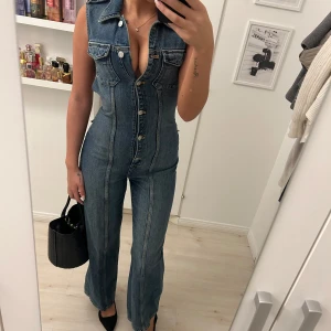 Zara jeans jumpsuit - Snygg ärmlös jeans jumpsuit med knappar framtill och öppen rygg. Köpt från Zara och är slutsåld överallt! Älskar denna men den har aldrig nånsin kommit till användning..