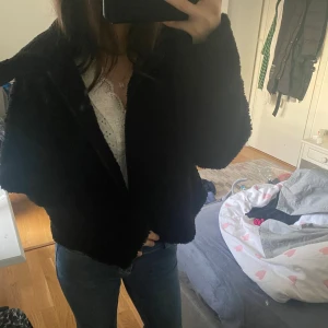 Svart teddyjacka - Mysig svart teddyjacka med dragkedja. Perfekt för kyligare dagar och ger en trendig look. Jackan har långa ärmar och en bekväm passform. Stlk M men passar mig som bär xs