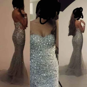 Glittrig axelbandslös långklänning - Exklusiv klänning från Cecilias mode. Köpt för 12.000kr. Kan behövas kemtvättas vid änden av klänningen annars är den i gott/nyskick. Storlek 34. Kan passa en smal 36a med mindre byst. Klänningen är axelbandslös och har en figurnära passform som framhäver silhuetten. Perfekt för en glamorös kväll!