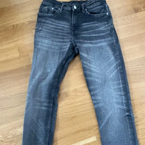Svarta jeans med snygg design - Snygga svarta jeans med en cool tvättad effekt. De har en klassisk femficksdesign och knappgylf. Perfekta för en avslappnad stil.
