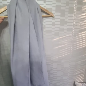Grå halsduk - Snygg och stilren grå halsduk som passar perfekt för kyliga dagar. Den har en enkel design och är lätt att matcha med olika outfits. Perfekt för att hålla dig varm och bekväm under höst och vinter.
