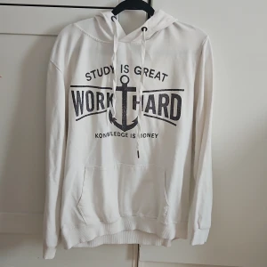 Vit hoodie med tryck - Säljer en vit hoodie med texten 'STUDY IS GREAT, WORK HARD' och ett ankare på framsidan. Hoodien har en klassisk design med känguruficka och justerbar dragsko i huvan.