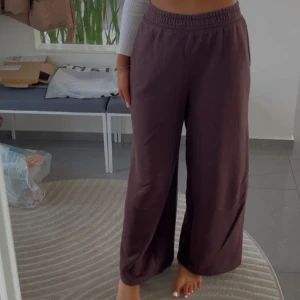 Bruna mjukis - Säljer ett par bekväma bruna byxor med elastisk midja. Byxorna har en loose passform och är perfekta för en avslappnad stil. De är tillverkade i ett mjukt material som ger en skön känsla hela dagen.