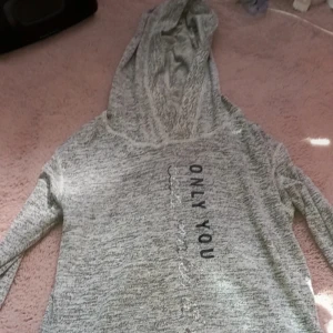 Grå hoodie med text - Säljer en grå hoodie med texten 'ONLY YOU' tryckt på framsidan. Tröjan har långa ärmar och en bekväm huva. Perfekt för en avslappnad stil.