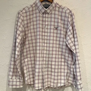  GANT skjorta i rutigt strl L - Snygg Gant-skjorta i rutmönster med en broderad logga på bröstet och ryggen. Innerfodret på kragen och innermuddarna är ljusblått/(grå). 