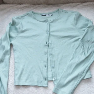 Ljusgrön ribbad kofta från Lager157 - Säljer en ljusgrön ribbad kofta från Lager157. Den har långa ärmar och knappar framtill. Perfekt för lager-på-lager-stil. Passar till både jeans och kjol.