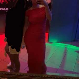 Röd axelbandslös långklänning - Elegant röd långklänning med axelbandslös design. Perfekt för festliga tillfällen med en smickrande passform som framhäver figuren. Använd 1 gång