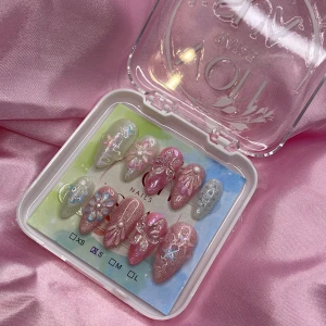 PearlSplash (S);Medium Almond - Set med mermaid gelé press-on naglar i storlek S: 15 mm, 11,5 mm, 12 mm, 11 mm, 9 mm , med både glittrig och cateye finish i rosa, silver och pastellblå. Naglarna har 3D-blommor, pärlor och stjärnor i blått, rosa och vitt. Mandelformade och superdetaljerade, perfekta för dig som vill ha något extra på naglarna.