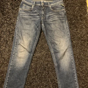 Blå Replay jeans Wallys straight fit - Säljer ett par blå Replay jeans, modell Wallys, med klassisk femficksdesign och snygga slitningar framtill. Jeansen har raka ben men ändå ganska slim passform, perfekta till en mer grisch stil. Materialet är tåligt jeans och färgen är en klassisk mellanblå denim.