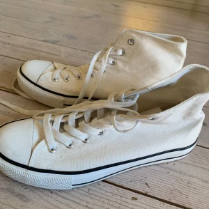 Vita liknade converse skor fast från Lager 157 - Använts 2 gånger. Klassiska vita höga sneakers från 157 i canvas med snörning och vit gummisula. Skorna har svart rand längs sulan och metallöljetter för en clean och tidlös look. Perfekta för dig som gillar enkel och stilren streetstil. INTE CONVENERSE DET ÄR LAGER 157