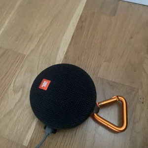 Jbl clip 2  högtalare - En jbl högtalare med bra ljud och liten och smidig. Ligger på nypris 590kr . Den är båda trådlös med bluetooth samt med kabel . Laddare finns ej. Men behövs bara en vanlig c kabel. Den har en hake så den går att haka i saker. Väldigt smidig och användbar.funkar exakt likadan som en ny. Du sparar hela 340kr! Laddaren finns på bild- ej original så medföljer ej!
