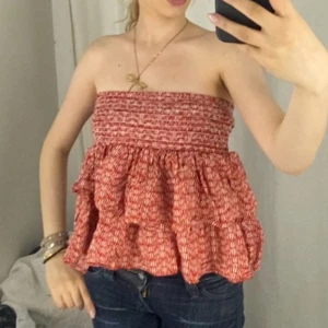 Röd volangig tubtopp - Supersöt röd bandeau tubtopp med volanger och smockad överdel. Perfekt för varma dagar och lätt att styla funkar att användas som kjol också 200kr