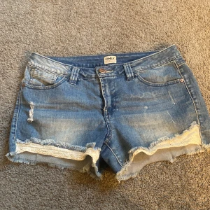 Blå jeansshorts med spets från ONLY - Snygga blå jeansshorts från ONLY med slitna detaljer och råa kanter. Storlek S/M 💗 Lågmidjade 