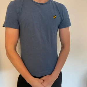 Blå t-shirt från Lyle & Scott - Snygg blå t-shirt från Lyle & Scott med klassisk gul logga på bröstet. Använd ett fåtal gånger så är i bra skick. Säljer då den är för liten! 
