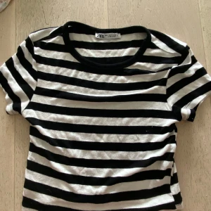 Randig t-shirt från Zara, svart/vit - Säljer en klassisk svartvit randig t-shirt från Zara i storlek S. T-shirten har korta ärmar, rund halsringning och är gjord i mjuk bomull. Perfekt för en chill och stilren look.