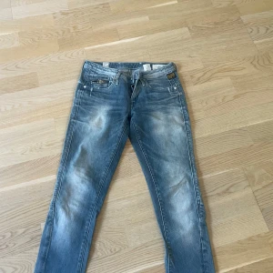 G-Star Raw ljusblå jeans - Säljer ett par snygga ljusblå jeans från G-Star Raw med slitna detaljer och coola dragkedjor på bakfickorna. Klassisk femficksmodell med broderad logga och patch bak. W:26, L:32 Skinny jeans passform
