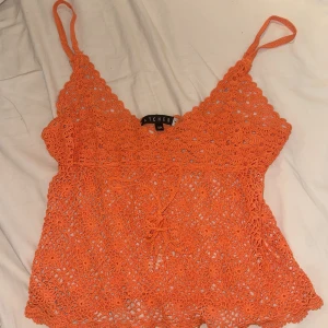 Somrig topp - Superfin orange virkad linnetopp från Watcher med smala axelband och v-ringning. Toppen har knyt under byster med en tråd med små pärlor i ändarna(bild3) och ett detaljerat blommönster i virkningen. Perfekt för sommarens alla tillfällen!💕 använd enstaka gång på semester❤️