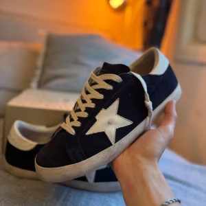 Mörkblå Golden Goose Skor - Snygga mörkblå sneakers från Golden Goose med vit stjärndetalj på sidan och vita snören. Storlek 43. Skick 9/10. Allt Og medföljer! 