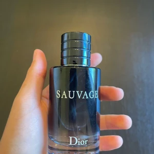 Dior Sauvage  - Säljer en flaska Dior Sauvage Eau de Toilette, 100 ml. Flaskan är cylindrisk i glas med en snygg mörkblå till svart gradient och silverdetaljer. Magnetisk kork med Dior-logga på toppen. En ikonisk herrdoft med fräsch och kryddig karaktär. Skulle säga att det är 90ml kvar. Passa på att köpa redan nu innan vintern för att slippa göra det sen. 