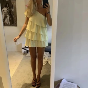 Gul one shoulder volangklänning - Superfin ljusgul kort klänning med flera volanger och one shoulder-design. Från Zara i storlek S. Har en fläck som är med på sista bilden. 