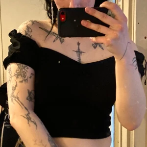 Svart topp med puffärmar från Bonangel - Supersöt svart croppad topp från Bonangel med puffärmar och lätt rynk vid bysten. V-ringad. Går att ha som off-shoulder också. Toppens material är mjukt och stretchigt, perfekt för en edgy och trendig look. Sitter snyggt över axlarna och har en smickrande passform.