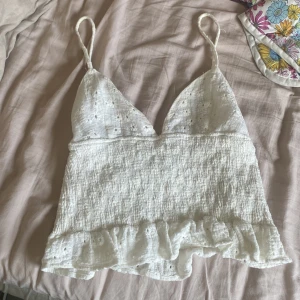 Vit broderad linnetopp från Zara XS - Superfin vit linnetopp från Zara i storlek XS. Toppen har smala axelband, broderade blommor på kuporna och volangkant nedtill. Materialet är lätt och luftigt, perfekt för varma dagar. Söt och feminin med en croppad passform. Pris kan diskuteras.