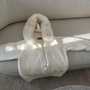Vit jacka med falskpäls från Alessa - Supermysig vit jacka från Alessa med fluffig luva av falskpäls. Storlek S och är helt oanvänd! 