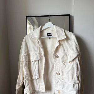 Beige jeansjacka från Zara XS - Snygg beige jeansjacka från Zara i storlek XS( passar för mig som har M) Jackan har klassisk krage, stora bröstfickor med lock och knappar framtill. Bra skick!