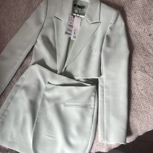 Ljusgrön kavaj och kjol från Zara - Snygg ljusgrön kostym från Zara med kavaj och matchande kjol som sitter ihop. Kavajen har klassisk krage och raka axlar, kjolen har en stilren design. Ger en mycket elegant och stilren look!!