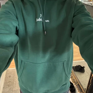 Grön hoodie från Polo Ralph Lauren - Mörkgrön hoodie från Polo Ralph Lauren med broderad logga på bröstet. Klassisk känguruficka framtill, dragsko i huvan och långa ärmar. Skön och stilren tröja i mjuk bomull, perfekt för chill dagar. Inga defekter över huvud taget!