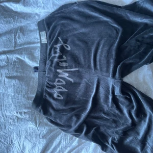 Svarta mjukisbyxor från Odd molly - Mysiga svarta mjukisbyxor från odd molly i sammetsliknande material. Byxorna har bred resår i midjan, snörning med rosett och avslappnad passform. Perfekta för chill eller träning. Snyggt tryck på rumpan och mjuk känsla mot huden.