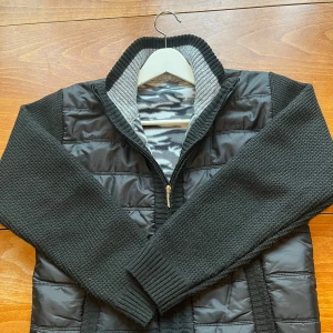 Svart Cardigan  - Snygg svart cardigan med quiltad framsida och rygg i syntet, stickade ärmar, dragkedja fram och ribbade muddar. Sitter riktigt bra och passar perfekt till jeans och sneakers. Grym för kallare sommardagar, höst och vår. Fickorna är igen sydda men går att sprätta upp. 10/10 skick! 🖤✂️