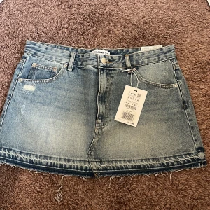 Blå jeanskjol från Pull&Bear - Säljer denna snygga jeanskjol. Den säljs då jag köpte den i tre storlekar, varav detta var en av dem som var för stora (och jag har tappat bort returneringsetiketten). Alltså är den ALDRIG använd och lapparna hänger kvar. Stängs med knapp och dragkedja framtill.