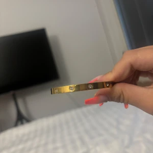 Guldigt armband med stenar - Snyggt armband i guldig metall med infattade runda stenar runt om. Stilren och klassisk design som ger en lyxig känsla. 