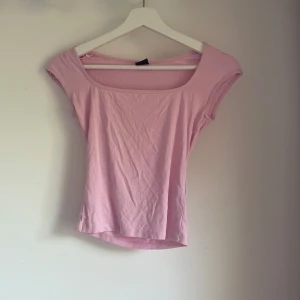 Ljusrosa topp från Gina Tricot - Supersöt ljusrosa topp från Gina Tricot i storlek XS. Toppen har en bred, fyrkantig urringning och är ärmlös med en smickrande passform. Perfekt att styla med jeans eller kjol för en fräsch look.