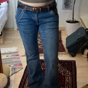 Blå bootcut lågmidjade jeans med broderade fickor - Snygga blå lågmidjade jeans med bootcut passform och coola broderade detaljer på bakfickorna. Jeansen är tajta men lite stretchiga och skönt mjukt tjockt jeansmaterlial. Bra kvalitet. Nytt skick, använt ca 2 gånger. Skriv för fler bilder!!