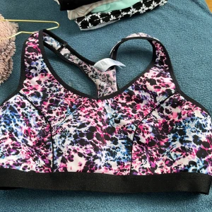 Färgglad sport-bh med leopardmönster - Sport-bh med coolt leopardmönster i rosa, blått, svart och vitt. Bred resår nedtill och brottarrygg för extra stöd. Perfekt för träning och ger en snygg look på gymmet. Tillverkad i stretchigt syntetmaterial som andas.