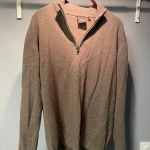 Beige kashmirtröja från Oscar Jacobson - Snygg beige tröja från Oscar Jacobson i mjuk kashmir. Tröjan har hög krage med half zip-dragkedja och långa ärmar. Perfekt för dig som gillar stilrena och klassiska plagg med exklusiv känsla.