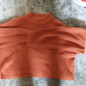 Rostbrun stickad tröja Gina Tricot - Säljer en rostbrun stickad tröja från Gina Tricot i storlek XS. Tröjan har hög hals, ribbade detaljer och lång ärm. Den är loose fit och perfekt för höst och vinter. Supermysig och enkel att styla till jeans eller kjol.
