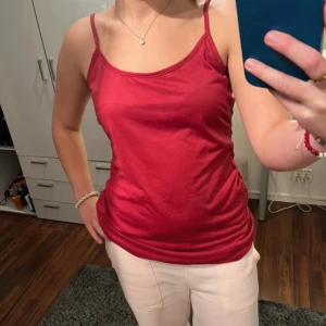 Röd/hot pink linnetopp med smala axelband - • enkel och snygg röd linnetopp med smala axelband och rundad halsringning. • toppen är figurnära och gjord i mjuk bomull, perfekt att styla med jeans eller kjol. • passar dig som gillar en clean och stilren look.