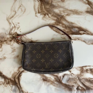 Louis Vuitton Väska - Säljer en klassisk Louis Vuitton axelväska i brunt skinn med ikoniskt monogrammönster och guldfärgade detaljer. Väskan har en smidig dragkedja och en kort axelrem i läder. Perfekt storlek för det viktigaste och en riktig statement piece.