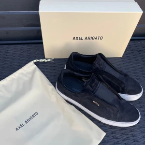 Axel Arigato 360 Laceless, storlek 45 - Ett par svarta Axel Arigato 360 laceless. Skorna är i fint skick och har använts vid ett dussin tillfällen. Original kartong och oanvänd dustbag medföljer. Perfekt för en avslappnad men stilren look.