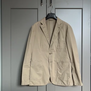 Aspesi blazer/kavaj - 🚨PRISET ÄR INTE HUGGET I STEN 🚨Hej! Jag säljer denna stilrena kavajen från det italienska lyxmärket aspesi. Den är beige (även om den ser lite mer grönaktig ut på vissa bilder pga ljuset) vilket gör den perfekt för härliga sommarkvällar! Säljer den eftersom den är lite liten på mig. Det finns inga defekter och den är i ett väldigt fint skick! Kavajen säljs inte längre, men nypris på liknande modeller ligger runt 5000-6000kr. Tveka inte på att höra av dig om du har några frågor!