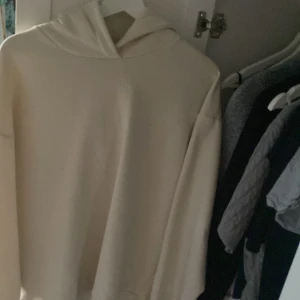 Beige hoodie med huva - En stilren beige hoodie med huva och klassisk passform. Perfekt för dig som gillar en enkel och clean look. Tröjan har långa ärmar och är gjord i ett mjukt material som känns skönt mot huden. lång hoodie