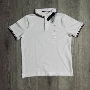 Vit pikétröja Tommy Hilfiger Xl i barn - Vit pikétröja från Tommy Hilfiger i klassisk modell med krage och knappar. Storlek XL i barn vilket motsvarar  en S och helt ny🤝