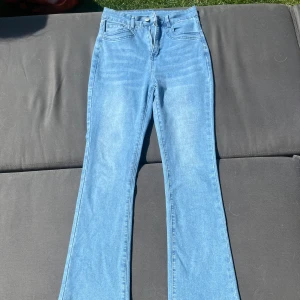 Ljusblå bootcut jeans - Snygga ljusblå jeans med bootcut-modell och hög midja. Klassisk femficksdesign och dragkedja fram. Perfekta för dig som gillar en retro vibe och vill ha ett par jeans som är lätta att styla.