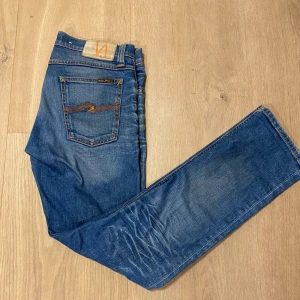 Blåa Nudie Jeans - Säljer ett par klassiska blå jeans från Nudie Jeans med snygga diskreta slitningar. Modellen har raka ben och slim passform. Perfekta för dig som gillar en tidlös jeansstil. Vid fler frågor kom privat💯